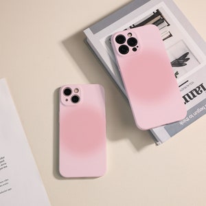 Puede incluir: Dos fundas de iPhone rosas con efecto degradado. Las fundas tienen una protuberancia de cámara elevada con tres lentes.
