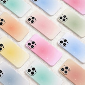 May include: A collection of smartphone cases featuring a soft gradient color palette including pastel pink, blue, yellow, orange, and green. Each case displays a subtle sparkling star pattern across the surface and a square camera cutout.