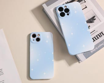 May include: Two light blue phone cases with a white star pattern and a gradient effect. The cases have a cutout for the camera lens.