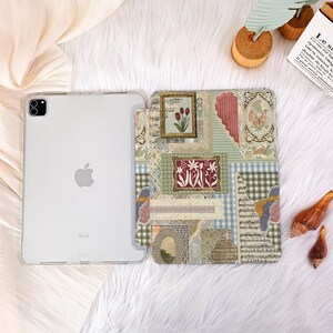 May include: An open iPad case with a clear back and a decorative front cover. The cover displays a collage of floral and patterned designs in green, pink, and beige. The design includes framed floral art and a butterfly motif.