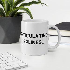 May include: White ceramic mug with black text that reads "REticulating SPLINES..."