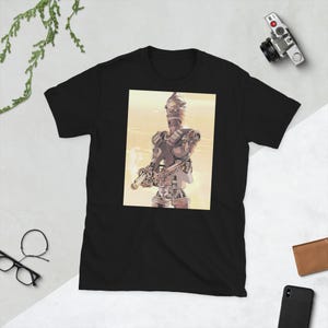 May include: Black t-shirt with a graphic of a robot character holding a blaster. The robot is in shades of grey and brown against a yellow background. The t-shirt is made of a soft, comfortable material.