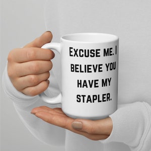 May include: White ceramic coffee mug with black text that reads "Excuse me. I believe you have my stapler."