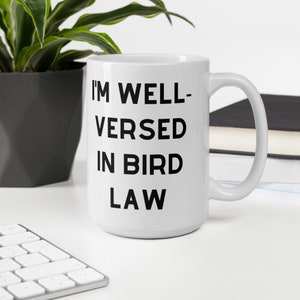 May include: White ceramic mug with black text that reads "I'm well-versed in bird law".