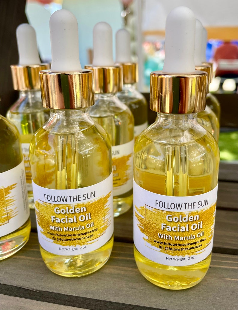 May include: Two amber glass bottles with gold lids and droppers filled with golden facial oil. The bottles have white labels with the text "FOLLOW THE SUN Golden Facial Oil With Marula Oil www.followthesunsoaps.shop IG: @followthesunsoaps Net Weight: 2 oz."