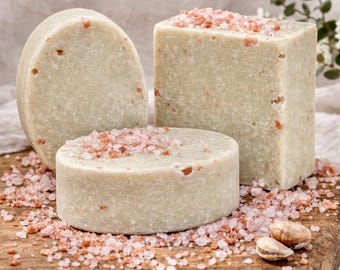 May include: Three handmade soaps in various shapes: a cylinder, a cube, and an oval. The soaps are light green with flecks of color and topped with pink Himalayan salt. The soaps rest on a wooden cutting board.