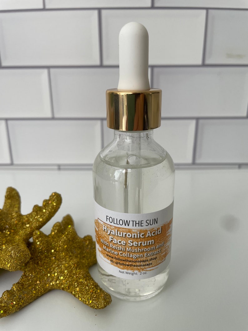 May include: A clear glass bottle with a gold lid and a white dropper top. The bottle is labeled "FOLLOW THE SUN Hyaluronic Acid Face Serum With Reishi Mushroom and Marine Collagen Extract www.followthesunsoaps.shop IG: @followthesunsoaps Net Weight: 2 oz."