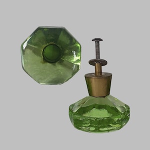 May include: A light green glass knob with an octagonal shape and a brass-colored metal base featuring a threaded bolt and washer. The text VINTAGE WANTAGE is visible at the top. The knob is shown from both a top-down and a side perspective.