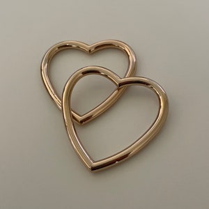 May include: Two gold heart-shaped hoops, one nested inside the other.