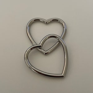 May include: Two silver heart-shaped metal rings, one nested inside the other.