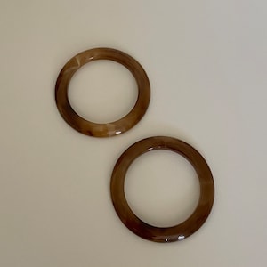 May include: Two brown and white marbled plastic rings. The rings are about 3 inches in diameter.