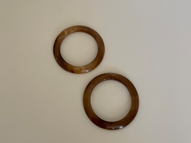 May include: Two brown and white marbled plastic rings. The rings are about 3 inches in diameter.