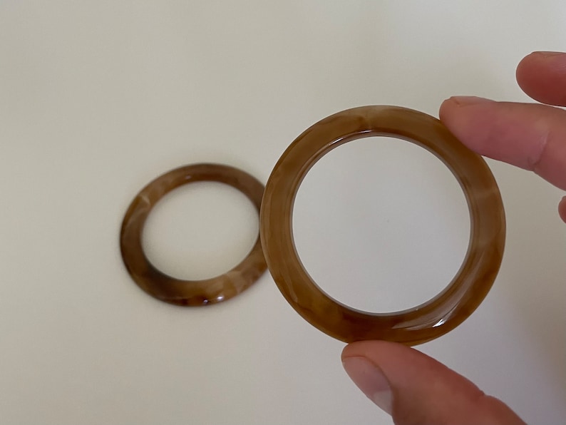 May include: Two brown plastic rings with a marbled pattern. The rings are about 3 inches in diameter.