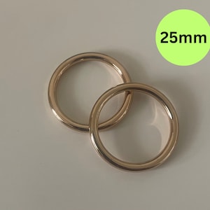 May include: Two gold-colored metal rings, each with a diameter of 25mm. The rings are interlocked.