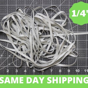 May include: A pile of white elastic cord, 1/4 inch thick, on a black grid surface.  The text "SAME DAY SHIPPING" is visible at the bottom of the image.
