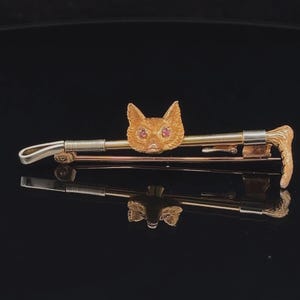 Puede incluir: Un broche de cabeza de zorro de oro con ojos de rubí, fijado en un alfiler de palo de oro y plata.