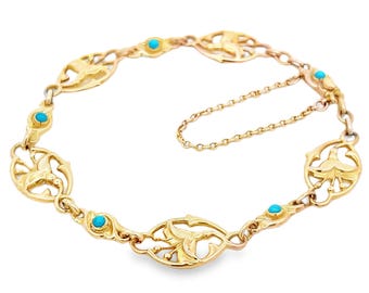 Puede incluir: Un brazalete de oro con una cadena delicada y piedras turquesa. El brazalete presenta un diseño repetitivo de pájaros y hojas estilizados.