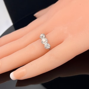Puede incluir: Un anillo de plata con tres diamantes redondos engastados en fila.