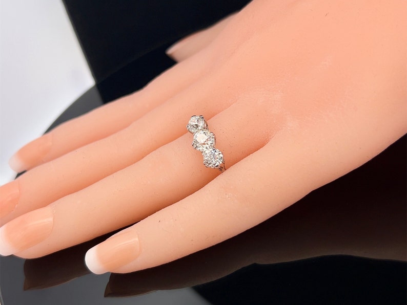 Puede incluir: Un anillo de plata con tres diamantes redondos engastados en fila.