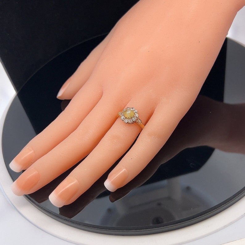 May include: A gold ring with a round, yellow opal gemstone surrounded by a halo of smaller diamonds.