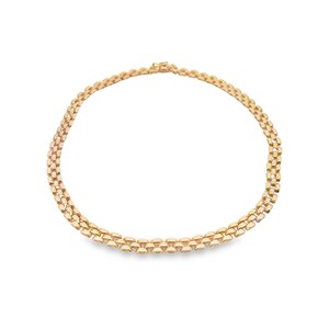 May include: A gold chain necklace with a delicate, interlocking pattern. The chain is made of multiple strands of small, rounded links.
