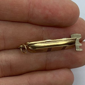 May include: A gold-colored charm in the shape of a speedboat with a ring for attaching to a necklace or bracelet.