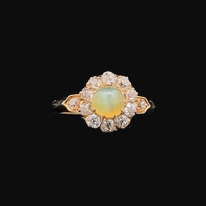 May include: A gold ring with a large, oval-shaped opal gemstone surrounded by a halo of smaller diamonds.