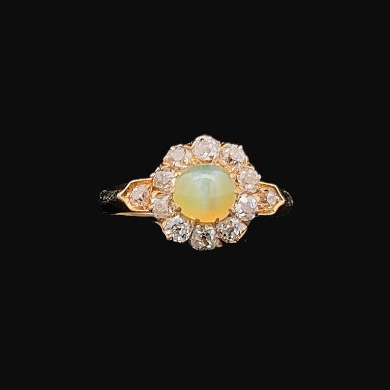 May include: A gold ring with a large, oval-shaped opal gemstone surrounded by a halo of smaller diamonds.
