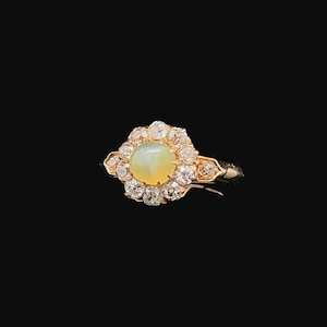 May include: A gold ring with a green opal gemstone surrounded by a halo of small diamonds.