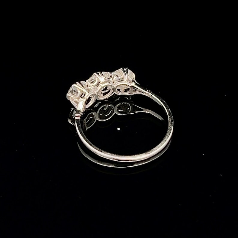 Puede incluir: Un anillo de banda de plata con cinco piedras redondas transparentes engastadas en una fila.