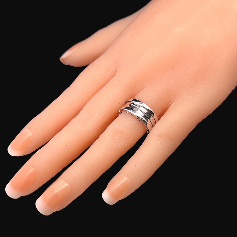 May include: A silver ring with three bands, each with a slightly different texture. The ring is worn on a model's finger.