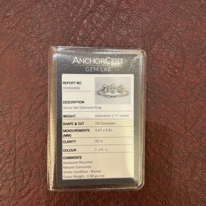 Puede incluir: Un primer plano de un anillo de diamantes con un certificado de Anchorcert Gem Lab. El anillo es un anillo de diamantes engastados con un peso estimado de 1,77 quilates. El diamante es un corte antiguo europeo con medidas de 4,87 x 5,81 mm. La claridad del diamante es VS 11 y el color es I-JK-L. El certificado tambi&eacute;n indica que los diamantes son naturales y que la condici&oacute;n de la cintura es bruta. El peso bruto del anillo es de 2,56 gramos.