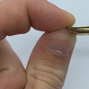 May include: A gold-colored metal key with a unique design. The key has a curved body and a small, intricate handle.