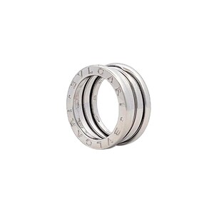 May include: A silver ring with the word "BVLGARI" engraved around the band. The ring is made up of three bands that are stacked on top of each other.
