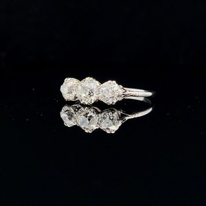 Puede incluir: Un anillo de plata con tres diamantes redondos engastados en fila. Los diamantes son transparentes y brillantes.
