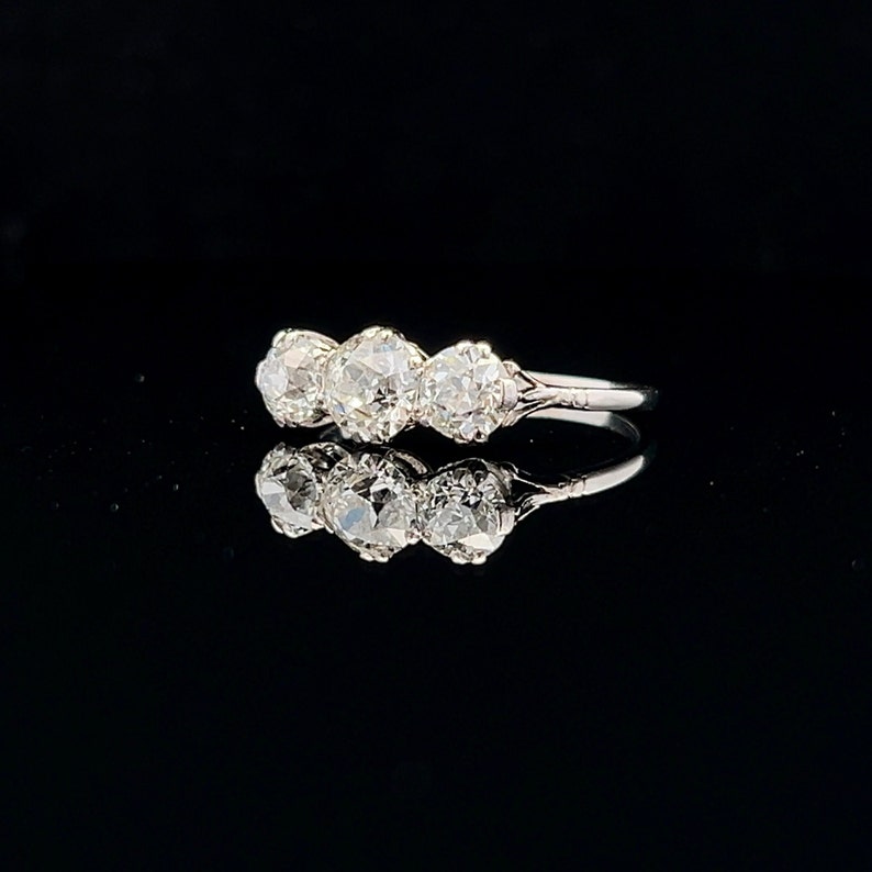 Puede incluir: Un anillo de plata con tres diamantes redondos engastados en fila. Los diamantes son transparentes y brillantes.
