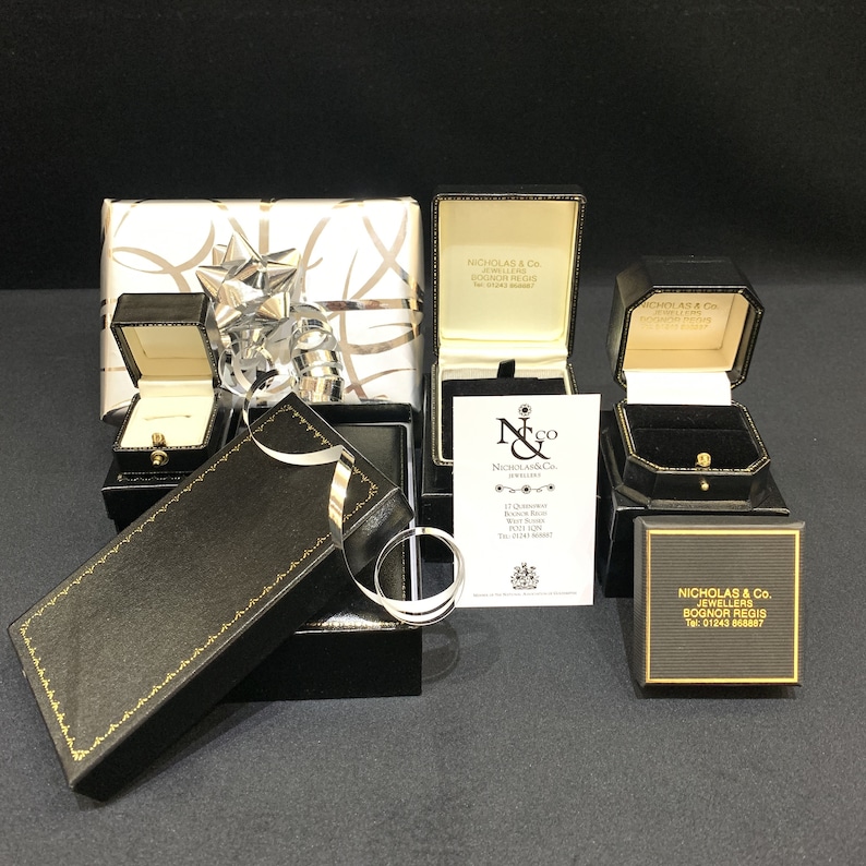 May include: Four black gift boxes with gold trim and a white gift box with a silver ribbon. The boxes are labeled "Nicholas & Co. Jewellers Bognor Regis".