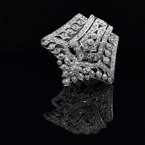 May include: A silver and diamond brooch with a geometric design. The brooch is set with small diamonds and has a floral motif in the center.