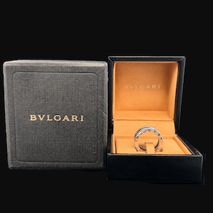 May include: A silver ring with the word "BVLGARI" engraved on it, inside a black and brown box with the same brand name.