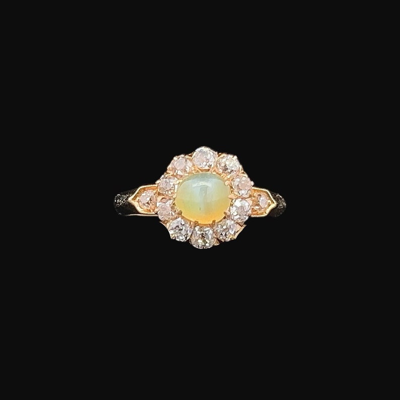 May include: A gold ring with a white opal gemstone surrounded by a halo of smaller diamonds.