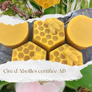Peut inclure: Gros plan sur des blocs de cire d'abeille en forme de nid d'abeille, avec un motif d'abeille sur certains blocs. Le texte "Cire d'Abeilles certifiée AB" est visible sur un fond blanc. L'image montre également une fleur rose et une abeille en vol.