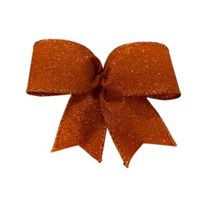 May include: A large, brown, glittery bow with gold trim. The bow is tied in a classic shape with two loops and a center knot.