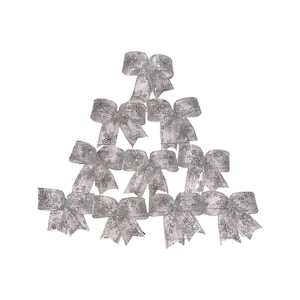 May include: Ten silver snowflake patterned bows arranged in a triangular shape. The bows are made of a sheer, sparkly material.