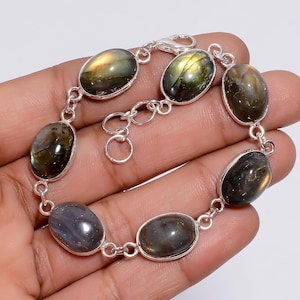 May include: A silver bracelet featuring oval-shaped labradorite gemstones. The stones are dark grey and green with iridescent flashes.