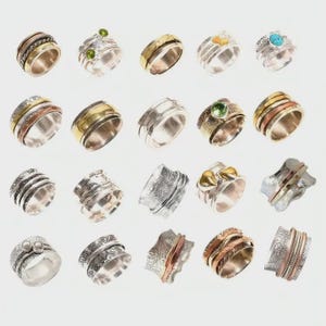 May include: A collection of silver rings with various designs. Some rings feature gemstones, while others have textured bands or decorative elements. The rings are displayed against a white background, showcasing their intricate details and diverse styles.