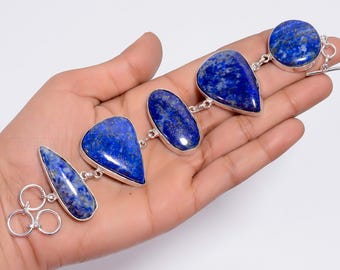 May include: A silver bracelet featuring five polished lapis lazuli gemstones in various shapes, including teardrop, oval, and round cuts. Each stone is set in a silver bezel and connected by silver links, finished with a toggle clasp closure.