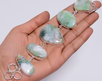 May include: A silver link bracelet featuring five polished, irregular, teardrop-shaped variscite stones. The stones display a marbled pattern of milky white, soft green, and dark forest green hues. The bracelet is secured with a silver toggle clasp.