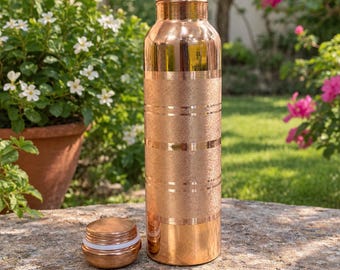 May include: A cylindrical copper water bottle with a polished neck and base, featuring a textured middle section accented by horizontal smooth bands. A matching copper screw-top lid with a white silicone seal sits beside the bottle.