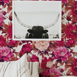 K&ouml;nnte beinhalten: Ein Schwarzwei&szlig;foto eines Bullenkopfes mit gro&szlig;en H&ouml;rnern ist gerahmt und an einer Wand mit einer floralen Tapete mit rosa und burgunderfarbenen Pfingstrosen aufgeh&auml;ngt.