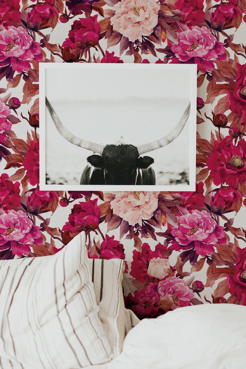 K&ouml;nnte beinhalten: Ein Schwarzwei&szlig;foto eines Bullenkopfes mit gro&szlig;en H&ouml;rnern ist gerahmt und an einer Wand mit einer floralen Tapete mit rosa und burgunderfarbenen Pfingstrosen aufgeh&auml;ngt.